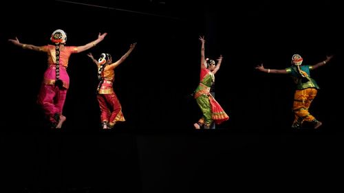 Group of people dancing against black background