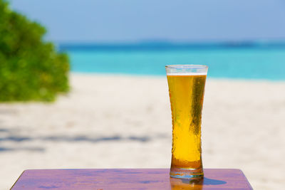 Close-up of beer glass on table with sea in background