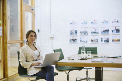 Portrait of smiling businesswoman using laptop computer in board room