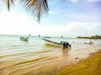 People and boats in sea against sky