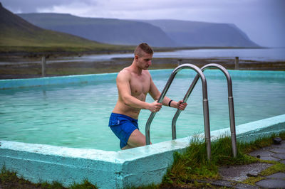 Full length of shirtless man standing in swimming pool