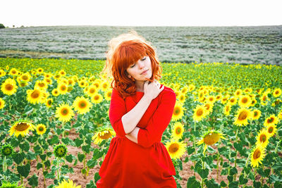 Beautiful woman standing amidst sunflower plants field