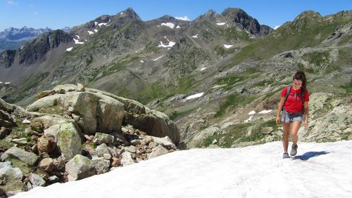 Rear view of man standing on rock against sky