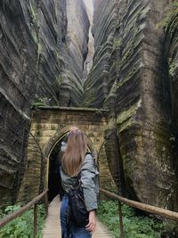 Rear view of woman standing against rock