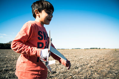 Boy holding model airplane on land