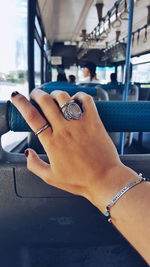 Close-up of woman hand wearing rings touching vehicle seat in bus