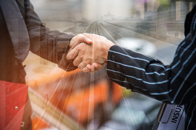 Double exposure of bridge and business people shaking hands