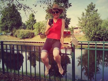 Full length portrait of woman standing on tree trunk