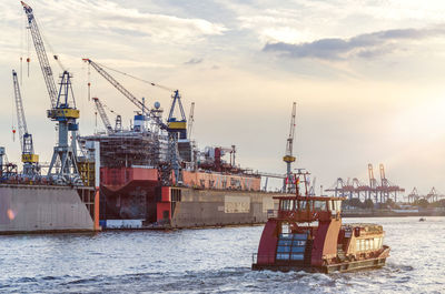 Cranes at harbor against sky