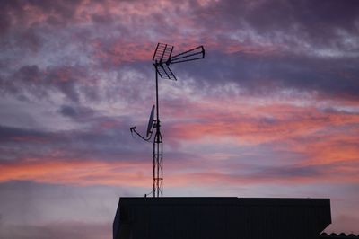 Low angle view of silhouette communications tower against sky during sunset