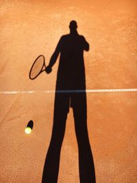 Shadow of man playing tennis at court