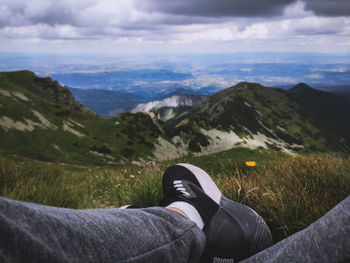 Low section of person on mountain against sky