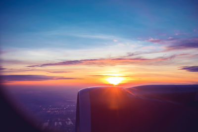 Close-up of airplane wing against sky during sunset