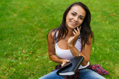 Portrait of smiling young woman sitting on field