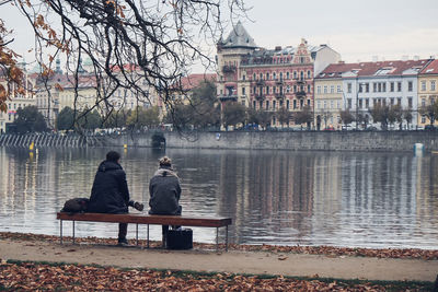 Rear view of people sitting on riverbank