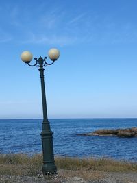 Street light by sea against sky