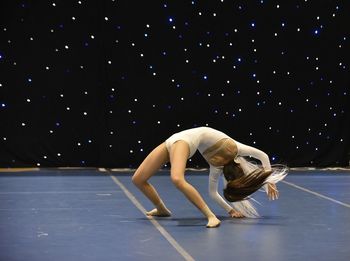 Young teenage girl in white jersey perform modern dance on stage