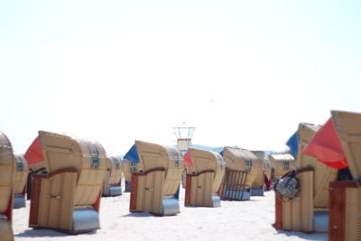Hooded beach chair on sand against sky
