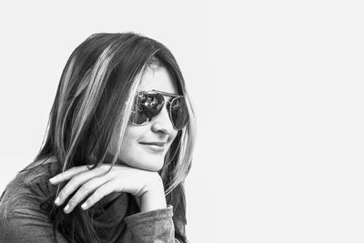 Young woman wearing sunglasses looking away against white background