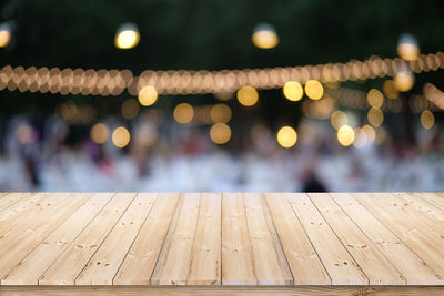 Wood plank on blur bokeh evening outdoor party or fair festival.