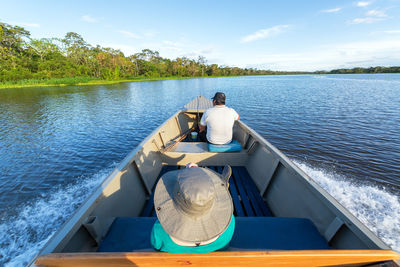 High angle view of tourist with guide in boat on river against sky