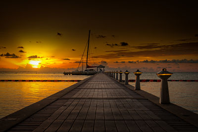 Pier over sea against sky during sunset