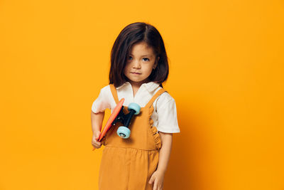 Young woman standing against yellow background