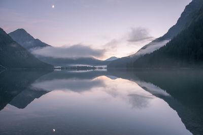 Scenic view of lake and mountains against sky during sunset