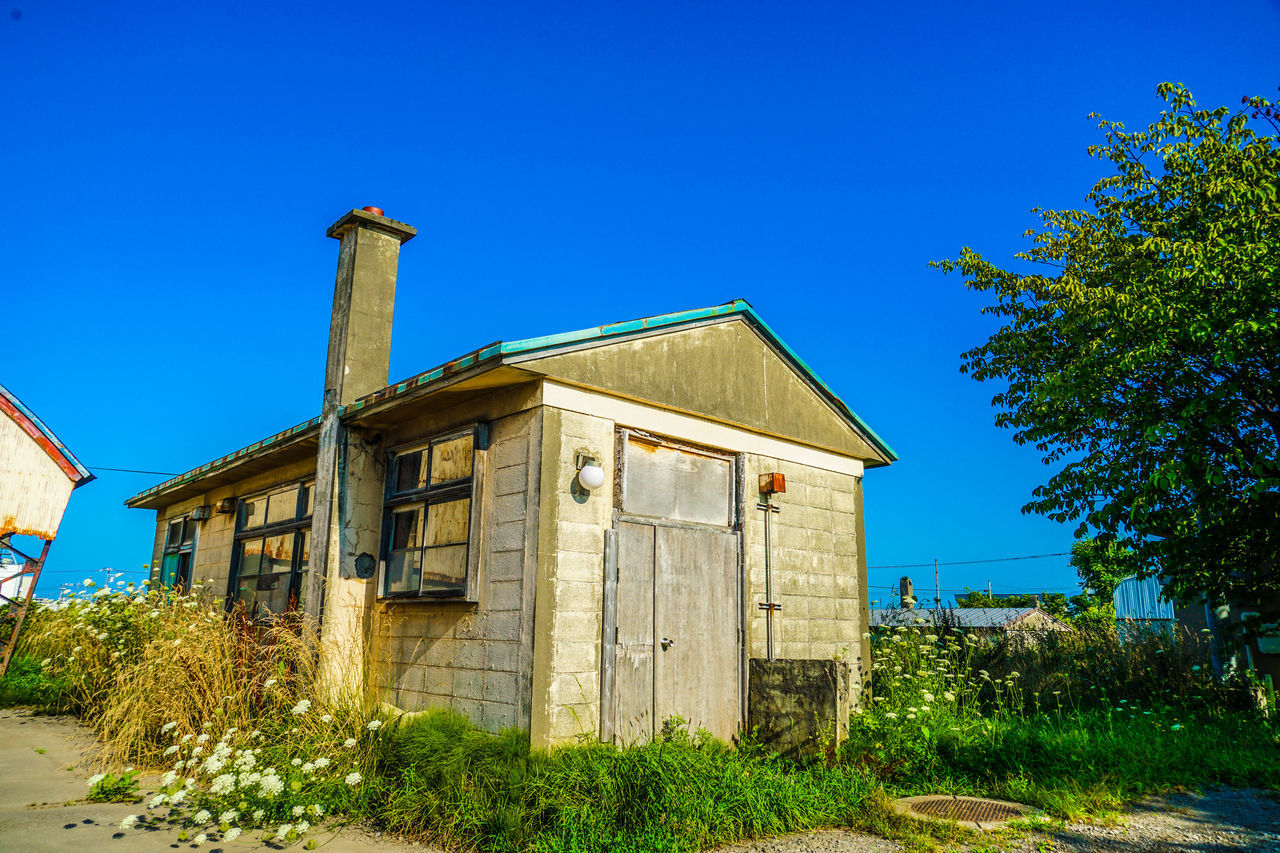 architecture, built structure, building exterior, rural area, sky, blue, house, building, nature, plant, clear sky, village, no people, estate, home, tree, day, rural scene, residential district, outdoors, landscape, cottage, old, sunny, town, shack, wood, residential area, land, sunlight, history