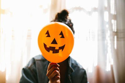 Midsection of person holding pumpkin at home