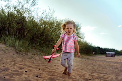 Full length of girl standing at beach against sky