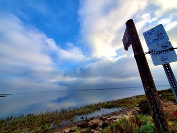 Low angle view of wooden post amidst sea against sky