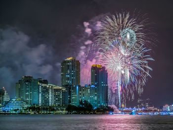 Firework display over skyscrapers in city at night