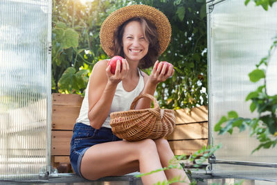 Portrait of young woman looking away while sitting on bench