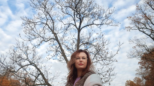 Portrait of young woman against bare tree