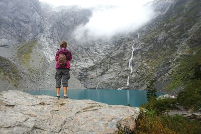 Young woman standing on rock by lake