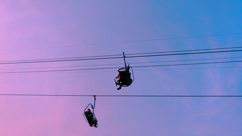 Low angle view of overhead cable cars against sky