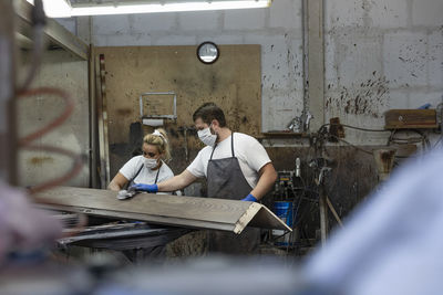 Carpenter team polishing wood while standing at factory