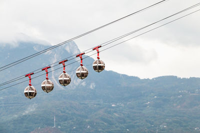 Overhead cable cars hanging against sky