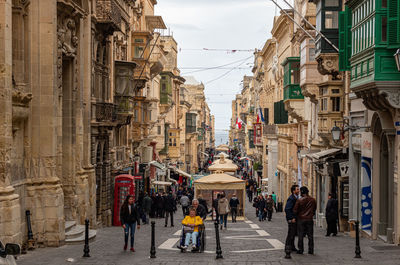 People walking on street amidst buildings in city