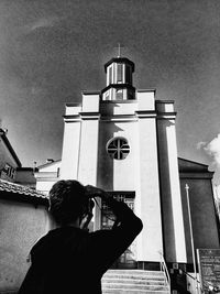 Low angle view of woman photographing through smart phone