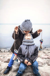 Girl in knitted grey hat sharing gloves with her frozen brother