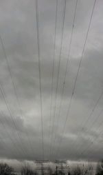 Low angle view of electricity pylon against cloudy sky