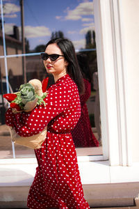 Portrait of young woman wearing sunglasses while standing in car