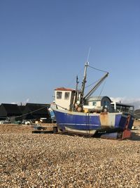 Ship moored on shore against clear blue sky