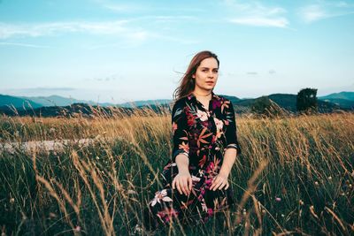 Young woman standing on field against sky