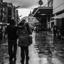 Rear view of people walking on street in city