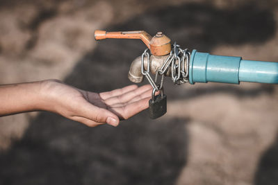 Cropped hands gesturing below faucet