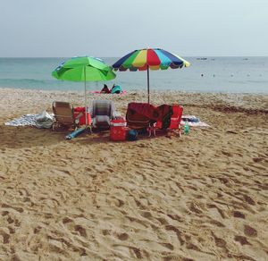 Lounge chairs and parasols on beach against sky