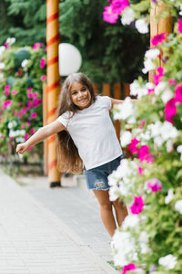 Cute girl having fun in the park in the summer among the flowers on summer vacation